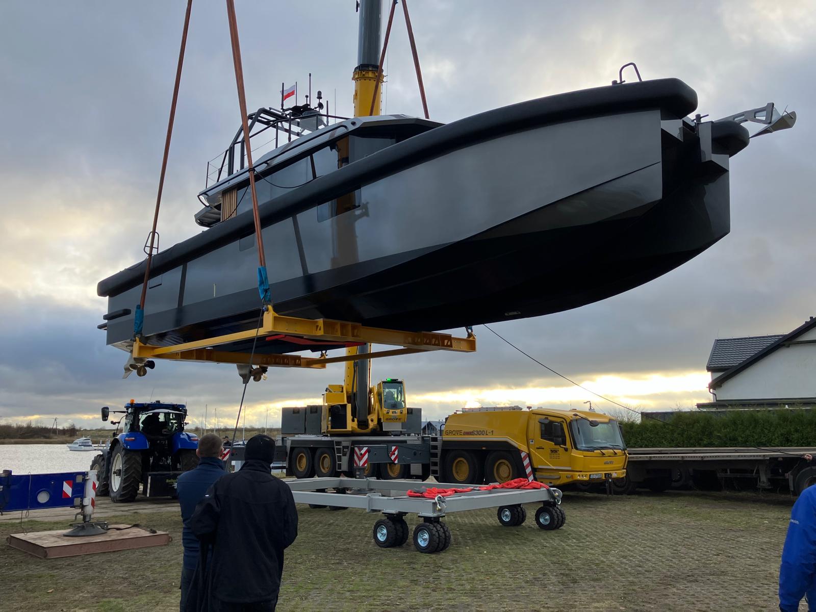 Yacht being lifted by crane onto transport cradle