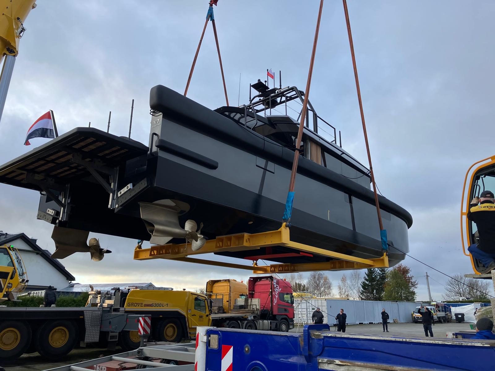 Crane lifting yacht at boatyard, side view