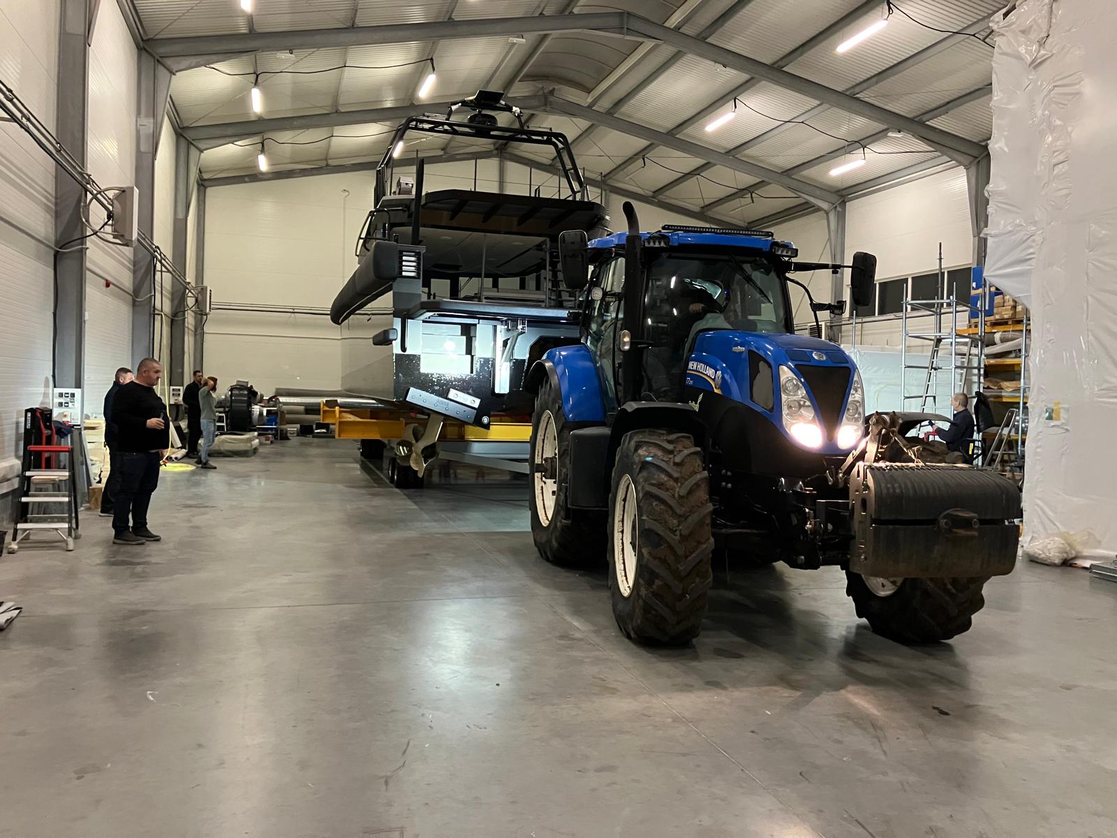 Tractor moving yacht on transport cradle in hangar
